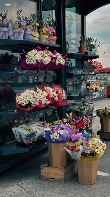 A display of various fresh floral arrangements featuring the vibrant colors of white, pink, purple, and yellow flowers at a flower shop. The arrangements include bouquets of chrysanthemums, lilies, an